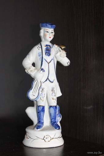 Декоративная, фарфоровая статуэтка, мальчика в костюме викторианской эпохи, держащего музыкальный инструмент.