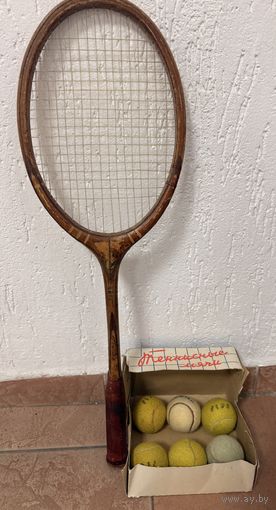 Винтажный набор, состоящий из деревянной теннисной ракетки и коробки с теннисными мячами.