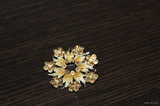Металлическая брошь со стразами в виде цветка.